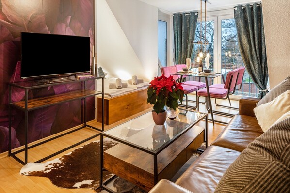 Un salon moderne avec une table basse en verre, un canapé en cuir et un téléviseur à écran plat posé sur un meuble.