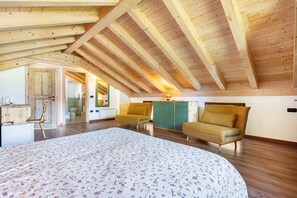 Un dormitorio con techo de madera, una cama con cubrecama floral, dos sillones amarillos y un mueble verde.