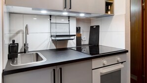 A modern kitchen with a stainless steel sink, black countertop, white cabinets, and a built-in oven. - Holiday Apartment 'Am Bahnhof Freiburg' with Wi-Fi (Freiburg im Breisgau)