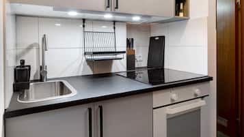 A modern kitchen with a stainless steel sink, black countertop, white cabinets, and a built-in oven.