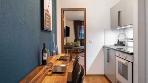 A modern kitchen with a wooden dining table, a built-in oven, and a TV in the background. - Holiday Apartment 'Am Bahnhof Freiburg' with Wi-Fi (Freiburg im Breisgau)