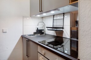 A modern kitchen with a black countertop, stainless steel sink, and a black hanging rack.