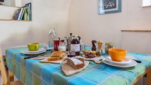 A table set with food, a book shelf, and a painting on the wall.