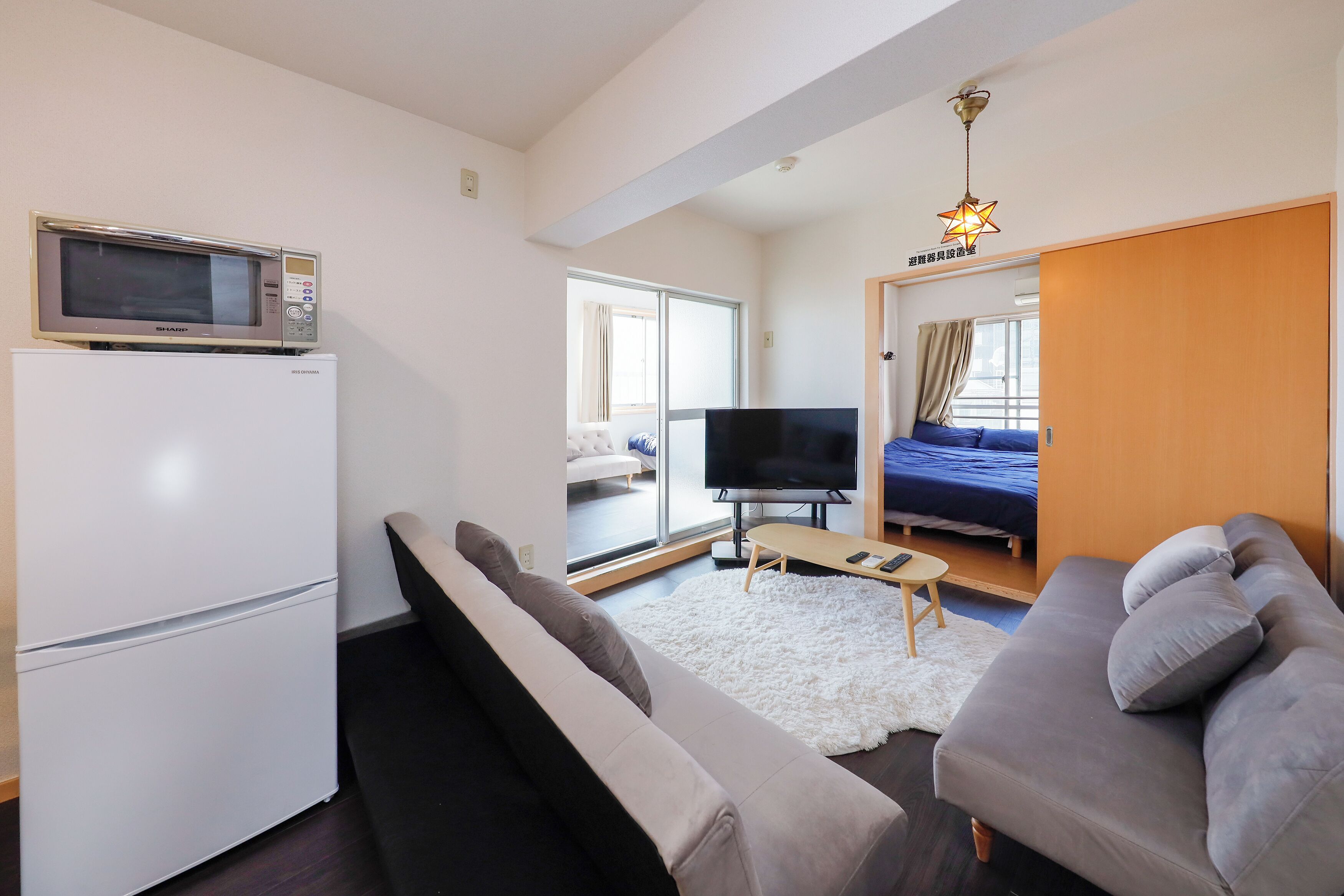 A compact living space with a kitchenette, a sofa, a TV, and a bed.