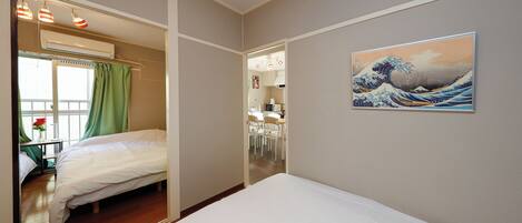 A hotel room with a bed, a painting, and a view of a dining area.