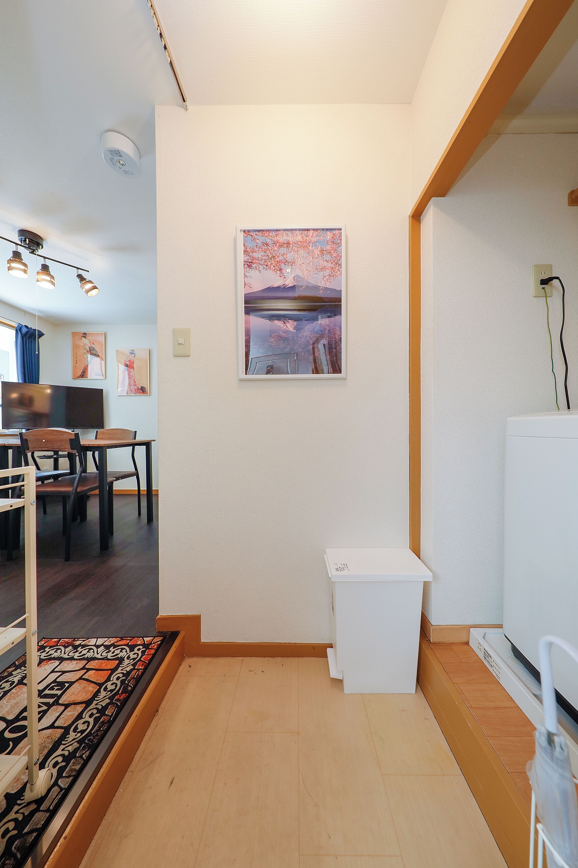 A compact living space with a dining area, a small white cabinet, and a mounted painting.