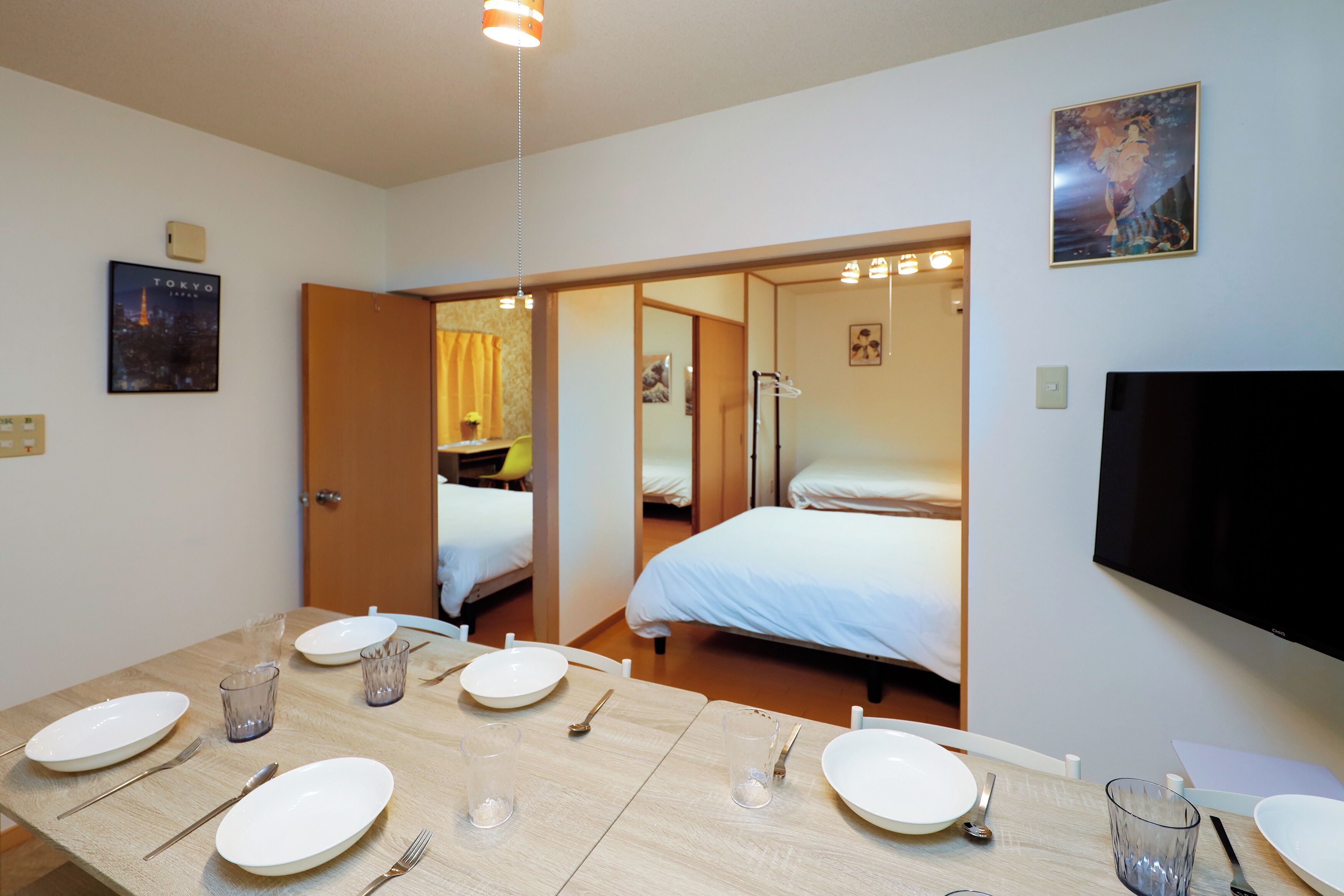 A hotel room with a dining area, a bed, a TV, and a painting on the wall.