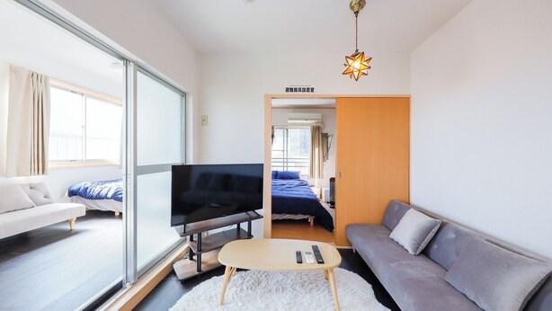 A modern hotel room with a sofa, a TV, a small table, and a bed. - Grace Heiwajima (Tokyo)