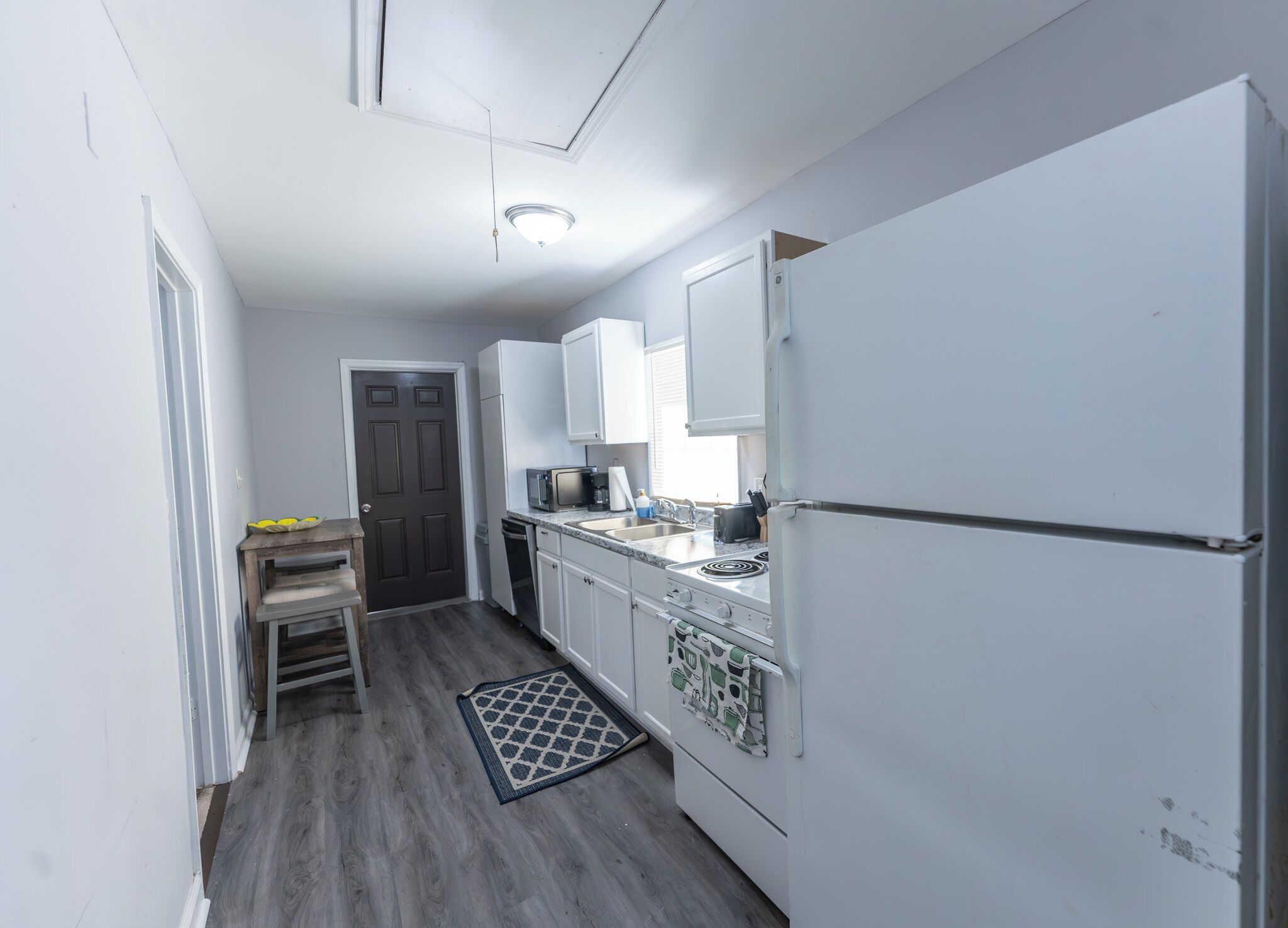A compact kitchen with white cabinets, a microwave, a stove, and a refrigerator.