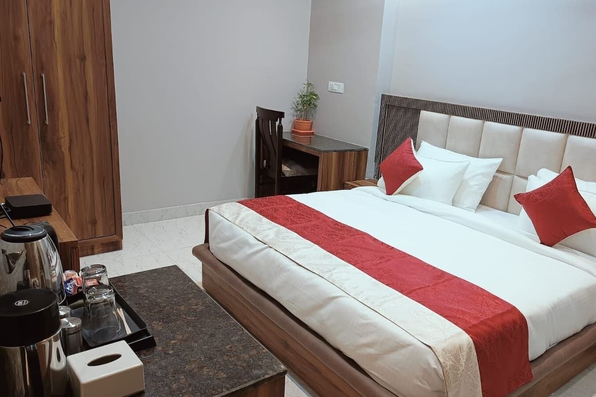 A neatly arranged bedroom with a bed, bedside tables, a small desk, and a chair.