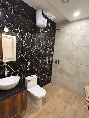 Un bagno con una parete in marmo nero, un water bianco, un lavandino e una doccia.