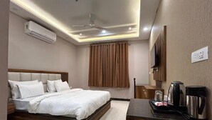 A hotel room with a bed, a desk with a coffee maker, and an air conditioner. - Hotel Wings Grand (Alwar)