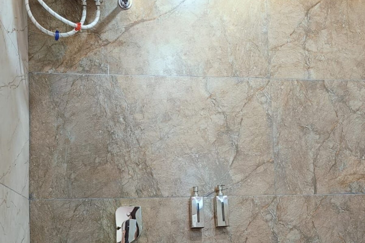 A bathroom with a shower, toilet, and a bucket.