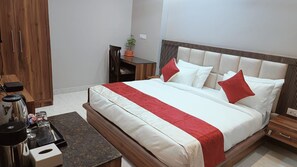 Un dormitorio ordenado con cama, mesitas de noche, un escritorio pequeño y una silla.