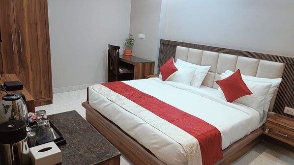 A neatly arranged bedroom with a bed, bedside tables, a small desk, and a chair. - Hotel Wings Grand (Alwar)