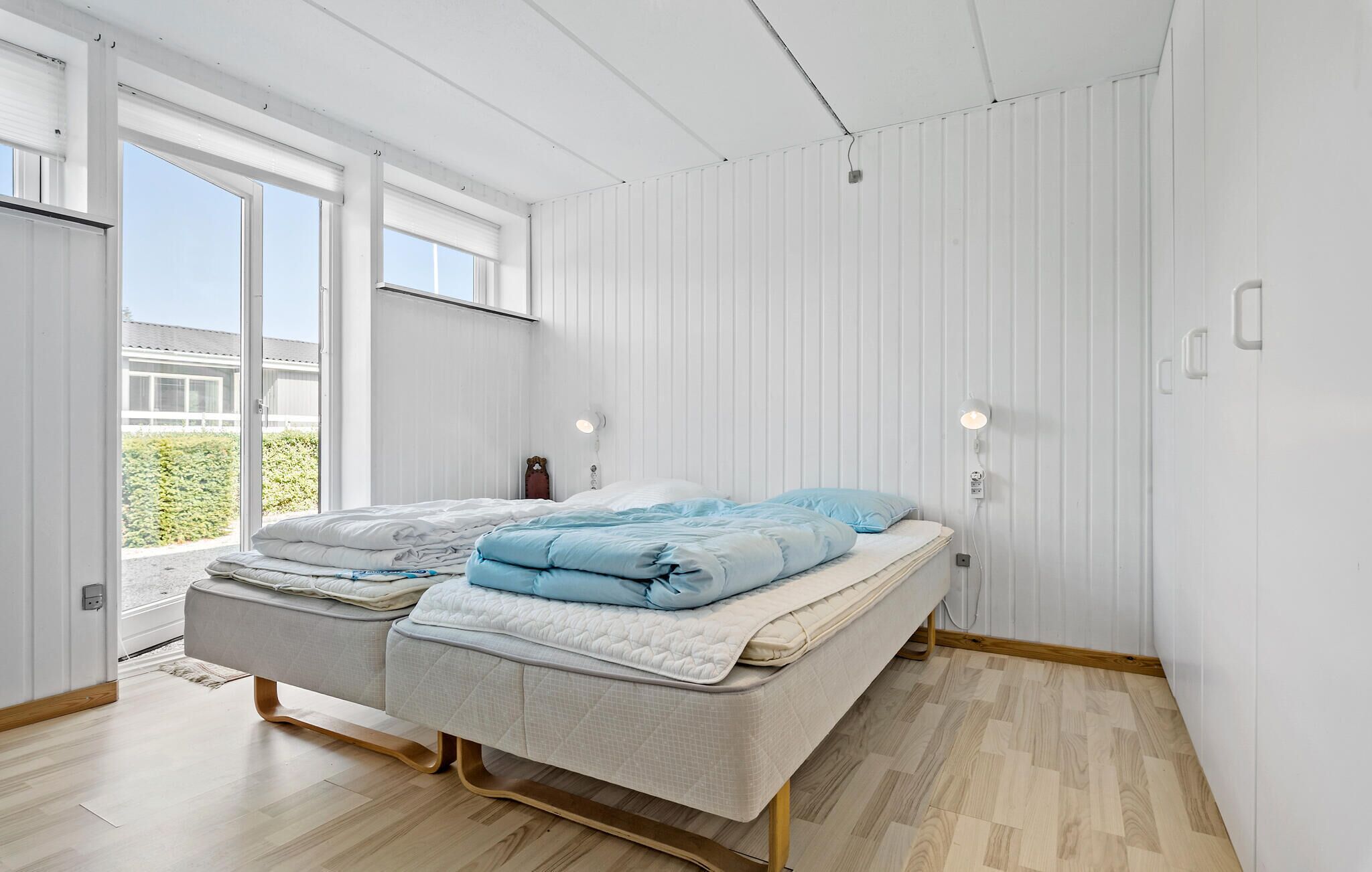 Een moderne slaapkamer met een bed, nachtkastjes en uitzicht op groen.