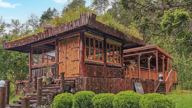 Eine rustikale Holzhütte mit großen Fenstern und einer Veranda.
