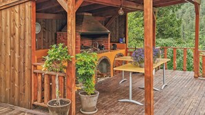 Eine Holzterrasse mit einem Backofen aus Ziegeln und einem Sitzbereich im Freien.