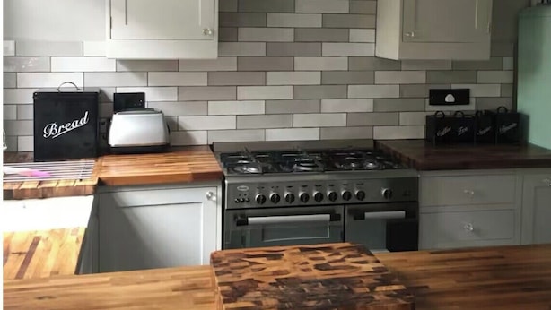 A kitchen with white cabinets, a gas stove, a bread box, and a hanging light fixture. - Shepherds Bush W12 Magical Townhouse nr Westfield (London)