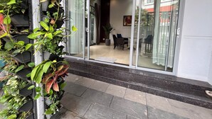 A hotel entrance with a glass door, a tiled floor, and a potted plant on the left.