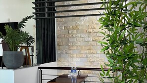 A modern dining area with a stone wall backdrop, a wooden table with benches, and a potted plant.