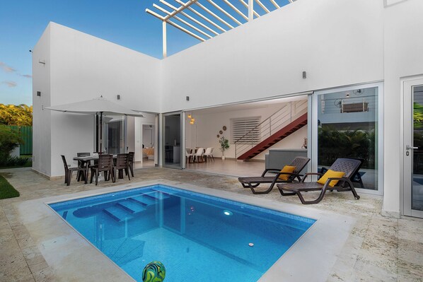 A modern house with a swimming pool, outdoor seating, and a staircase leading to an upper level. - Villa in Playa Mueva Romana  – Steps from Beach! (San Pedro de Macorís)