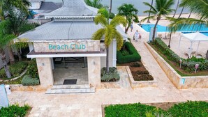 Un club de plage doté d’une entrée carrelée, de palmiers et d’un espace piscine.