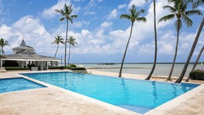 Une piscine dotée d’un espace couvert, de palmiers et offrant une vue sur la plage.