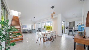 Un grand espace de vie comprenant un escalier, une table à manger avec des chaises et un coin cuisine.