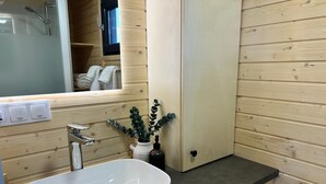 Ein Badezimmer mit Waschbecken, Spiegel, Handtuchhalter und einer Holzwand.