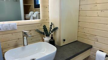Een badkamer met een wit wastafel, een spiegel, een handdoekrek en een houten wand.