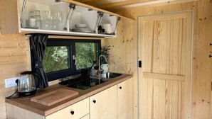 Eine kleine Küche mit Holzschnitzereien, einem eingebauten Herd und einem Fenster mit Vorhang.