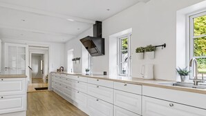 Een moderne keuken met witte kastjes, een houten aanrechtblad en een groot raam voor natuurlijk licht.