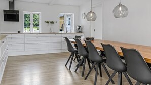 Een moderne keuken met witte kasten, een houten eettafel en zwarte stoelen.