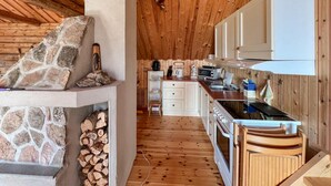 Una cocina acogedora de estilo cabaña con detalles de piedra, armarios de madera y una chimenea de piedra.