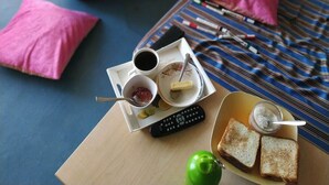 A room with a bed, a whiteboard, and a table with food and a remote control. - Oak Land House (Manali)