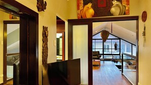 A modern interior with a large flat-screen TV, wooden flooring, and a view of a balcony with outdoor seating. - 3bedroom Penthouse at Asiana Villas  (Boracay Island)