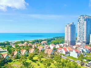 A coastal residential area with multiple-story buildings, a clear view of the ocean, and lush greenery. - SeaStay Condotel The Song Vung Tau (Ho Chi Minh City)