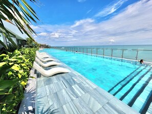 A swimming pool with clear blue water, surrounded by a glass barrier and a tiled deck. - SeaStay Condotel The Song Vung Tau (Ho Chi Minh City)