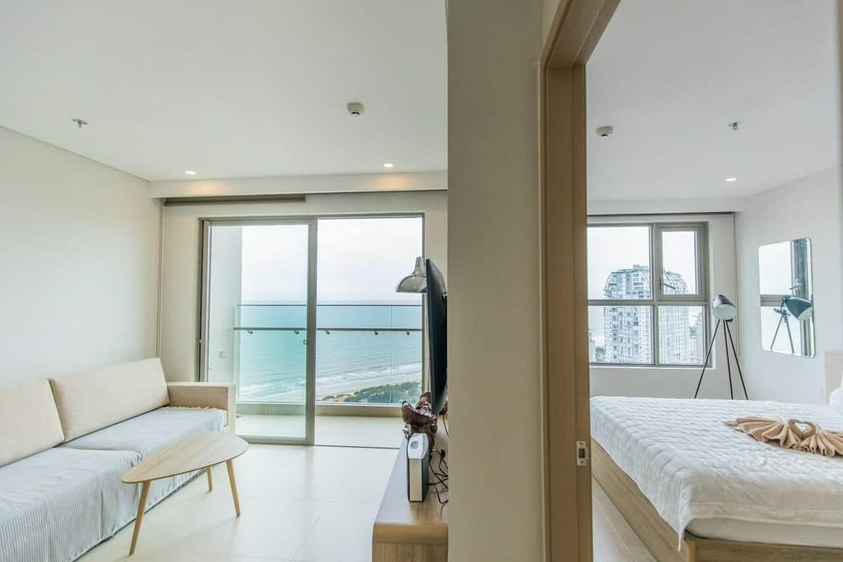 Quarto moderno com uma janela grande, um sofá, uma cama e uma escrivaninha.