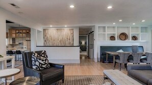 A modern living room with a sofa, a coffee table, and a dining area with a table and chairs. - The Treehouse: Spacious Retreat with Theater Room, Fire Pit & Mountain Views (Orem)
