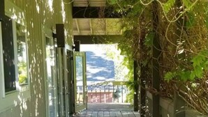 A covered walkway with a tiled floor, flanked by walls with windows and a view of a mountain in the distance. - The Treehouse: Spacious Retreat with Theater Room, Fire Pit & Mountain Views (Orem)
