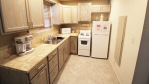 Una cocina compacta con armarios color beige, un microondas, una estufa y un refrigerador.