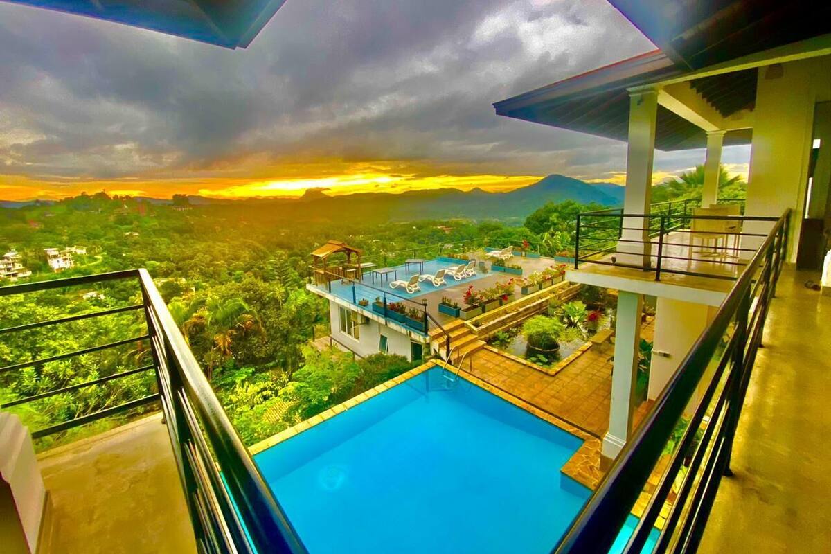 A swimming pool with a view of a lush landscape and a sunset.