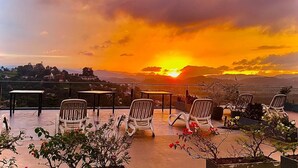 A terrace with chairs and tables overlooking a sunset. - 390 Villa Vista (Kandy)