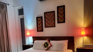 A hotel room with a large bed, two bedside tables, a wall-mounted air conditioner, and three decorative wall pieces. - 390 Villa Vista (Kandy)