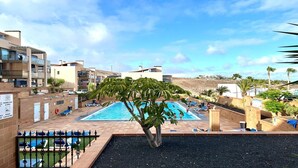 Ein Pool auf dem Dach mit Liegestühlen, umgeben von Gebäuden und Palmen.