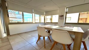 Ein Konferenzraum mit großem Tisch, vier Stühlen und großen Fenstern mit Blick auf Gebäude.