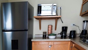 A kitchen with a stainless steel refrigerator, a microwave, a coffee maker, and a blender on the counter.