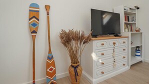 A room with a white dresser, a television on top, and two decorative paddles leaning against the wall. - Cozy apartment in Dziwnów with WiFi (Dziwnów)